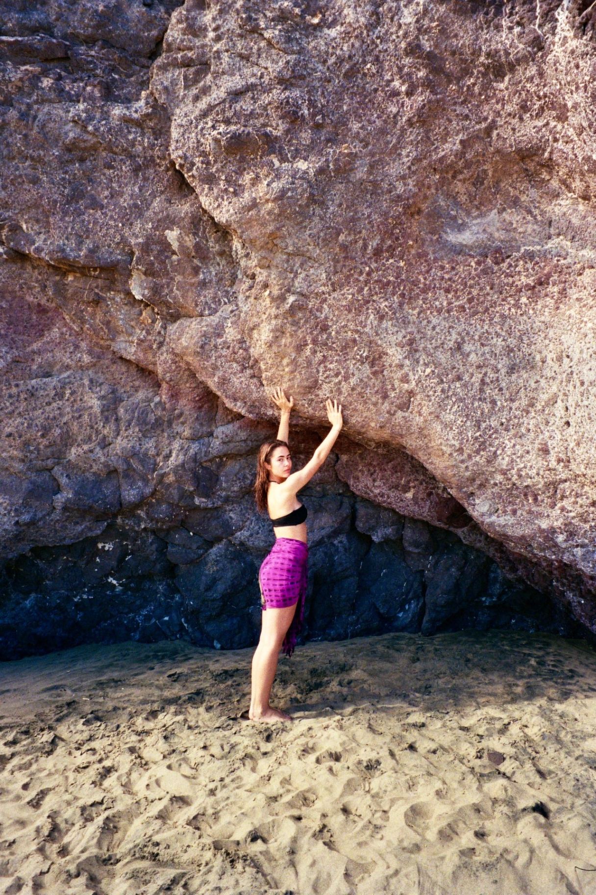 A figure pressing palms against a sun-warmed sea cliff